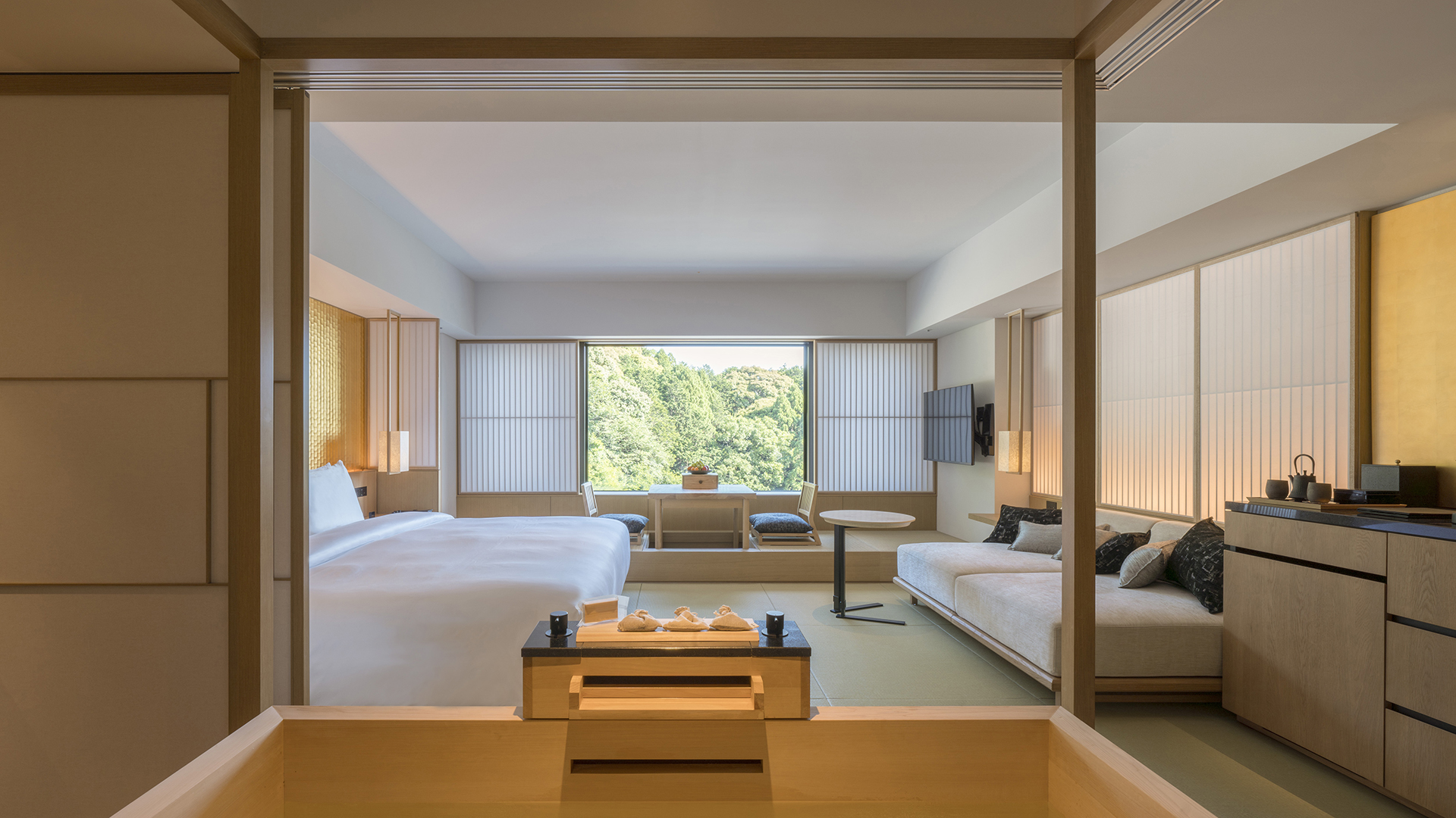 Room with serene decor showcasing a bed, seating area, and nature view at Banyan Tree Higashiyama Kyoto.